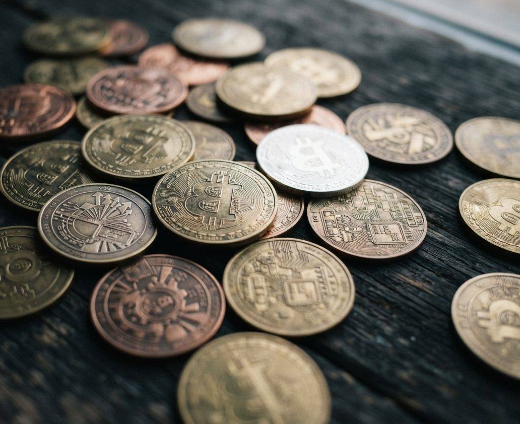 Close up of metallic bitcoin coins resting on a dark surface.